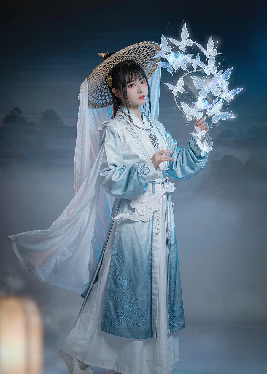 A woman in a Taoist mystic-style white and azure hanbok robe with cloud embroidery, holding a butterfly fan, soft ink-wash backdrop with paper lanterns.
